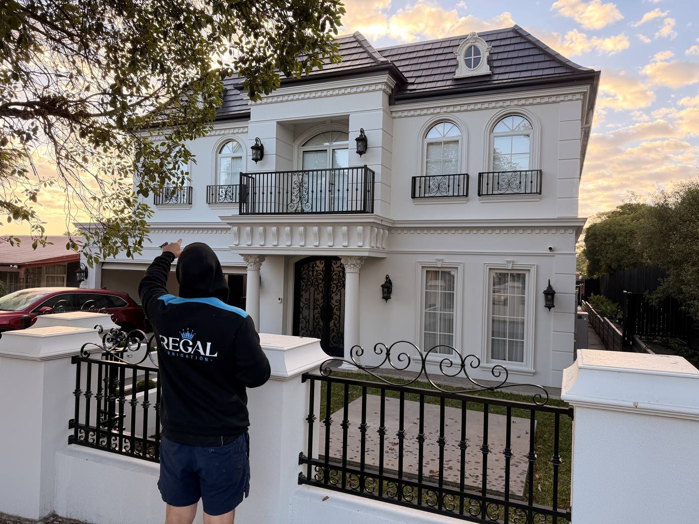 Reaching up mid-task at the grand home frontage, logo visible