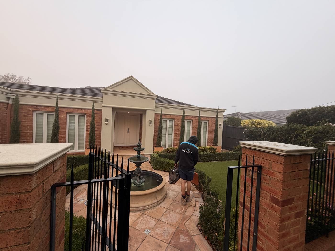Crouched by the brick-pillar entrance, premium paved garden