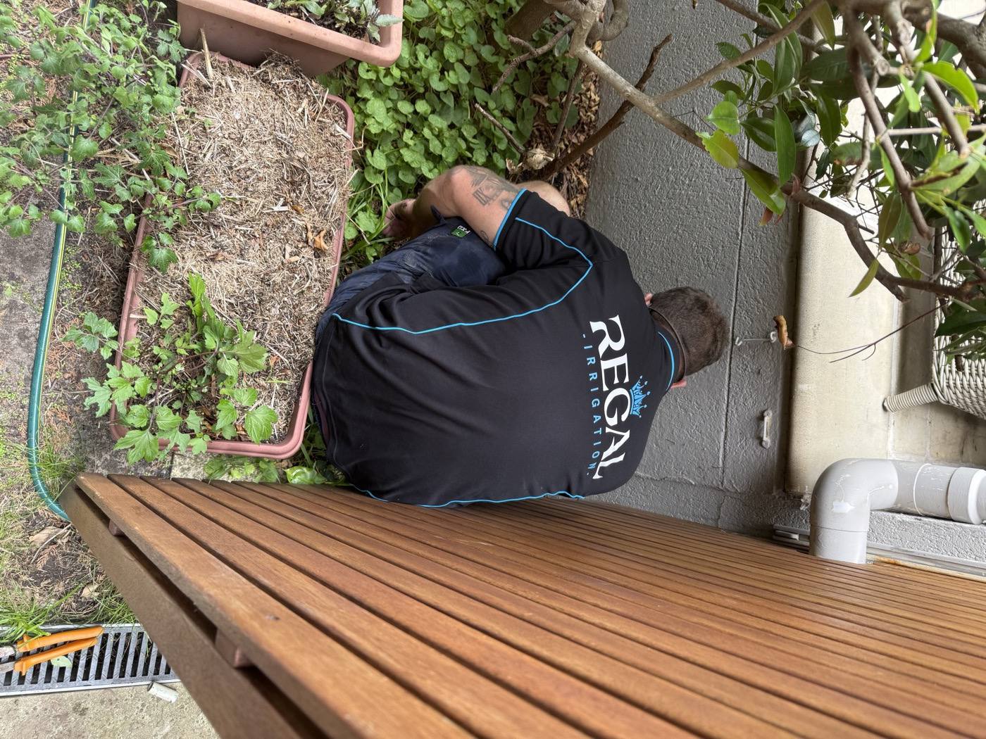 A Regal Irrigation team member on site, in branded shirt, working on a system
